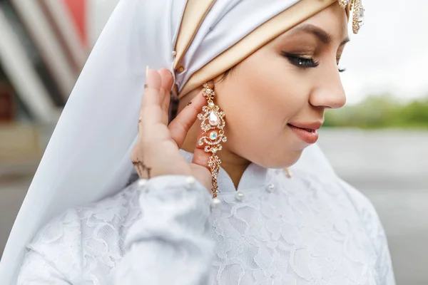 Очаровательная мусульманская арабская невеста в свадебном платье и хиджабском платке, крупным планом на ювелирных украшениях и серьгах — стоковое фото