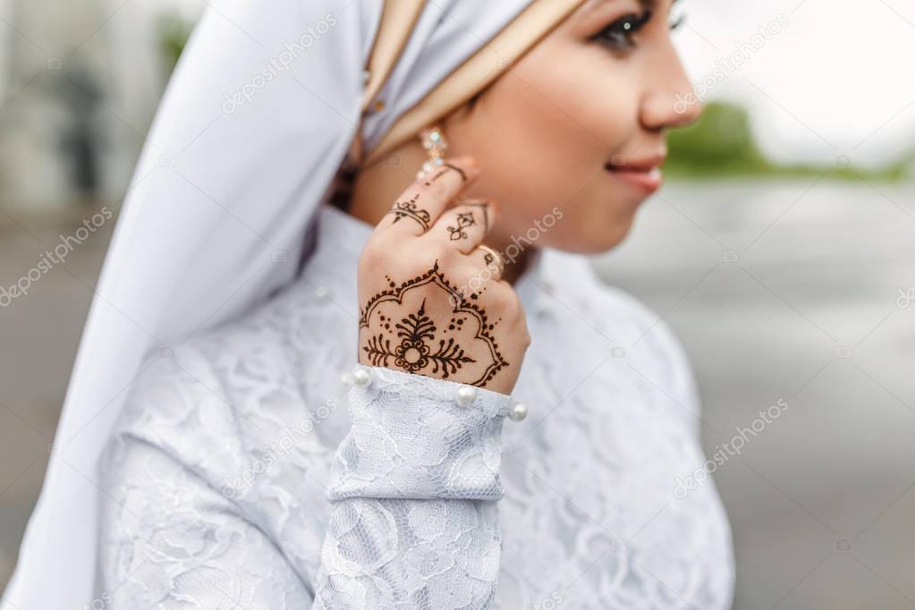 Charming muslim arabic bride in nikah wedding dress and hijab headscarf, close-up on jewelry and earrings