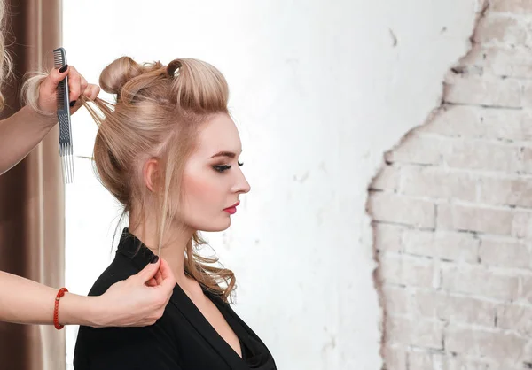 Cabeleireiro faz penteado da noite close-up no cabelo loiro de mulher de negócios no salão de beleza — Fotografia de Stock