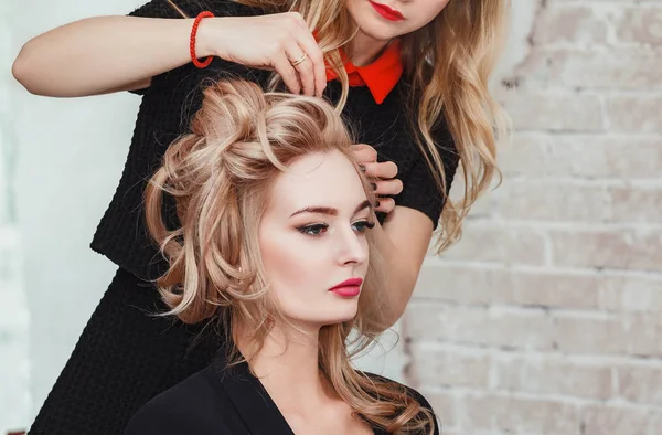 Cabeleireiro faz negócio à noite penteado close-up no cabelo louro arenoso de mulher bonita — Fotografia de Stock