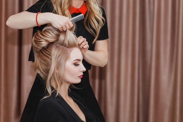 Cabeleireiro faz penteado da noite close-up no cabelo loiro de mulher de negócios no salão de beleza — Fotografia de Stock