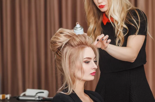 Cabeleireiro faz penteado da noite close-up no cabelo loiro de mulher de negócios no salão de beleza — Fotografia de Stock