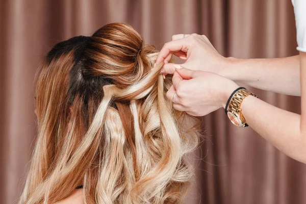 Hermosa chica rubia con el pelo largo haciendo un peinado de noche profesional en un salón de belleza — Foto de Stock