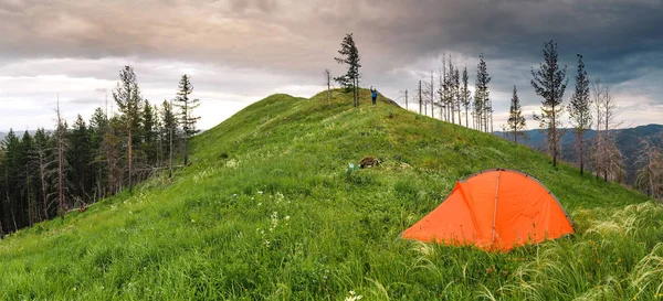 Помаранчевий пішохідний намет на вершині пагорба під свіжою травою, концепція літнього відпочинку на відкритому повітрі — стокове фото