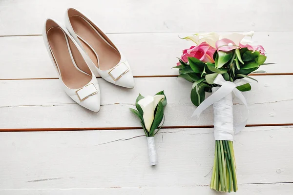Samenstelling van bruiloft ochtend details en accessoires. Bruids boeket en schoenen op een houten achtergrond — Stockfoto