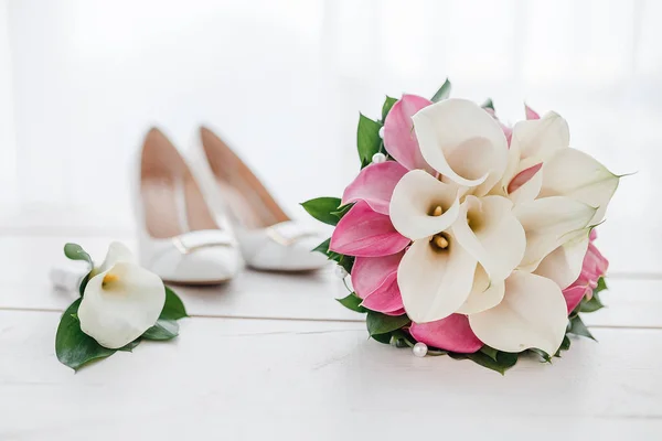 Samenstelling van bruiloft ochtend details en accessoires. Bruids boeket en schoenen op een houten achtergrond — Stockfoto
