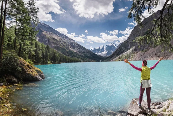 Woman traveler with open arms admiring the view of the famous beautiful turquoise lake Shavla in the mountains of Altai, Russia — Stock Photo, Image