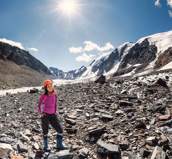 Joven montañista en un casco cerca de la cima del paso de la montaña en medio de rocas y glaciares — Foto de Stock