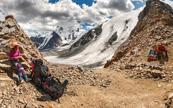 Joven montañista en un casco cerca de la cima del paso de la montaña en medio de rocas y glaciares — Foto de Stock