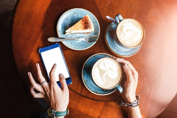 Mobil akıllı telefon Café kadın elinde bir close-up fincan kahve ve kek, düz Üstten Görünüm — Stok fotoğraf