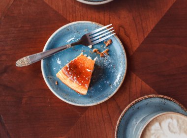 Kafe, düz görünüm masaya yiyecek kalıntıları. Kupa kahve ve çatal ile bir tabak bir peynirli kek kırıntıları ile