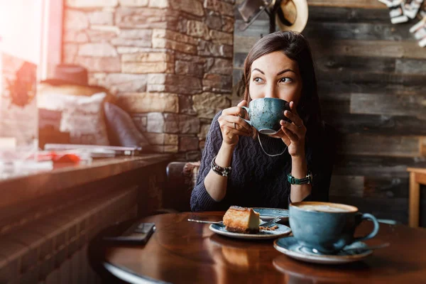 Красива азіатська жінка п'є гарячу каву або чай з старовинної чашки в сучасному лофт-кафе — стокове фото