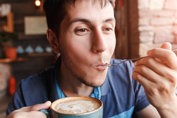 Молодий чоловік насолоджується кавою з шматочком торта в кафе — стокове фото