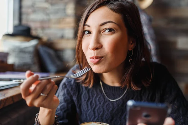 Красивая молодая азиатская женщина сидит в кафе и ест вкусный торт — стоковое фото