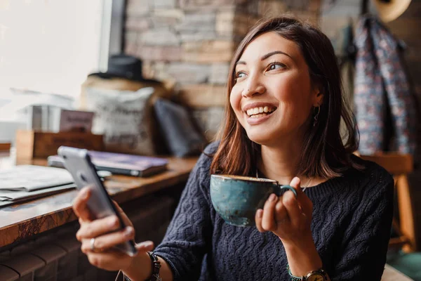 Young charming asian woman calling with cell phone while sitting alone in coffee shop — Stock Photo, Image