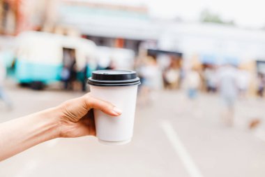 Tek kullanımlık paket servisi olan restoran kahve fincanı şehir sokak arka planda tutan el