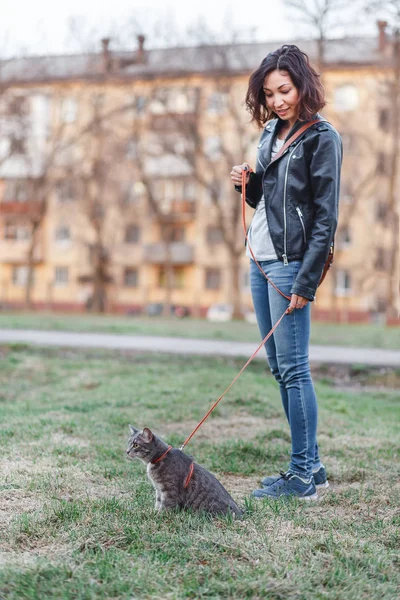 Vacker flicka promenader med en katt i koppel nära huset — Stockfoto