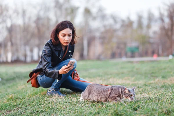 Güzel kız evin yanında bir leash üzerinde bir kedi ile yürüyüş
