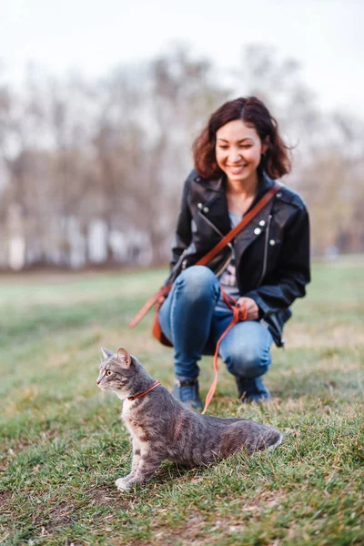 Güzel kız evin yanında bir leash üzerinde bir kedi ile yürüyüş