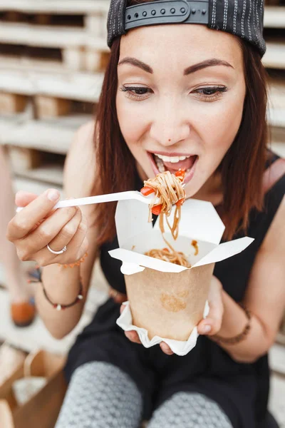 Joven mujer comiendo wok asiático fideos cocina de llevar caja en el fondo urbano de la calle —  Fotos de Stock