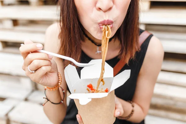 Красивая женщина ест азиатский фаст-фуд из коробки на вынос. Вкусная лапша Вок — стоковое фото