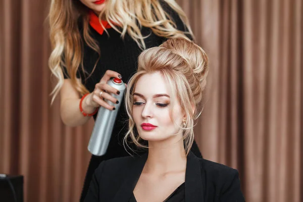 Vista de perto de um coiffeur de cabeleireiro faz o penteado da tarde ao modelo loiro no salão — Fotografia de Stock