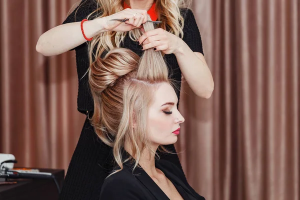 Mulher loira beleza no salão de cabeleireiro fazendo uma noite ou casamento estilo de cabelo — Fotografia de Stock
