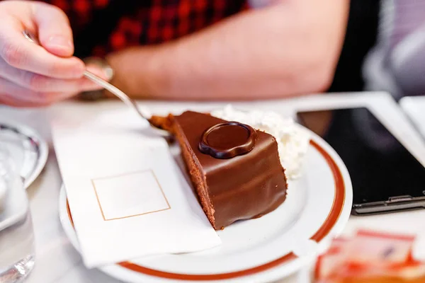 Hombre comiendo con tenedor una rebanada de pastel de Sacher en el plato —  Fotos de Stock