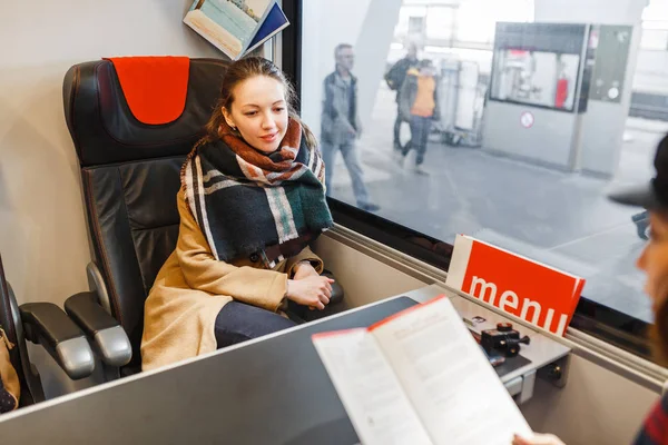Una joven europea viaja en un cómodo tren de lujo y mira pensativamente por la ventana — Foto de Stock