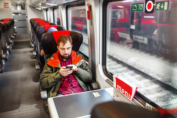 Открытое изображение красивого мужчины, работающего на смартфоне в современном поезде — стоковое фото