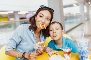 Anne ve oğlu patates kızartması ve kapalı birlikte eğlenerek yemek.