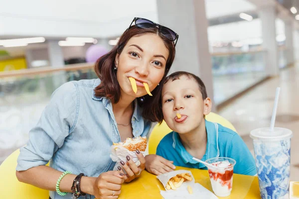 Anne ve oğlu patates kızartması ve kapalı birlikte eğlenerek yemek.