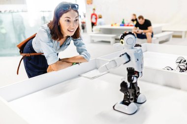 Genç yetişkin kadın Sergisi oyuncak robot bakarak