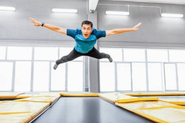 Bir genç atlama ve fitness salonunda trambolin üzerinde uçan mutlu adam yerleştirmek