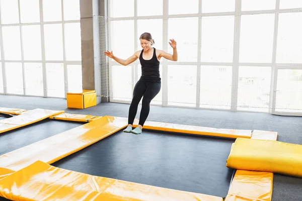 Mladá žena amatérský akrobatické sportovec, skákání a cvičení na trampolíně interiéru, moderní hobby a fitness koncept — Stock fotografie