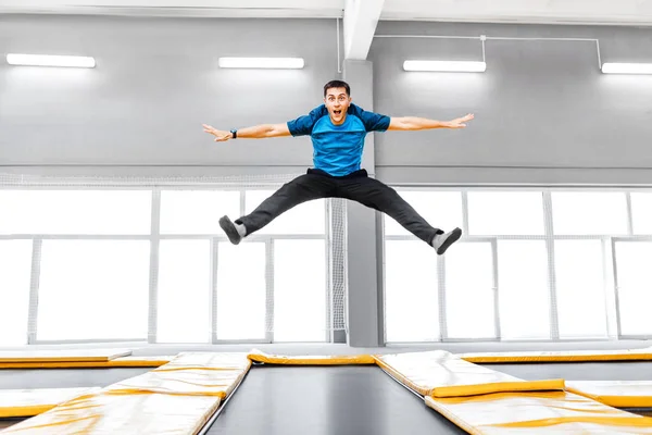 Mladé fit šťastný muž, skákání a létání na trampolíně v posilovna — Stock fotografie