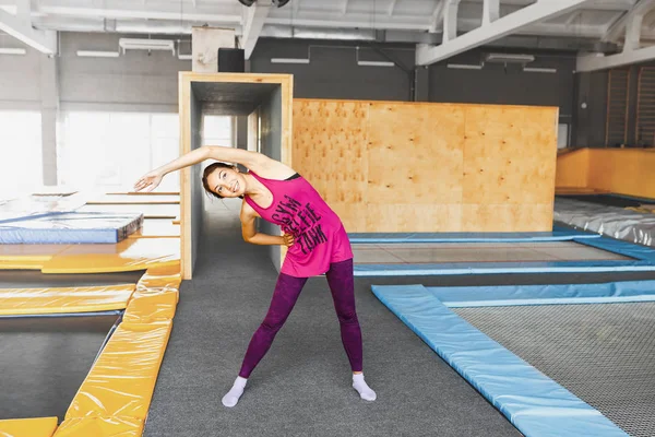 Vacker ung kvinna i sportkläder gör stretching och värmer upp innan du gör lite motion på studsmatta — Stockfoto