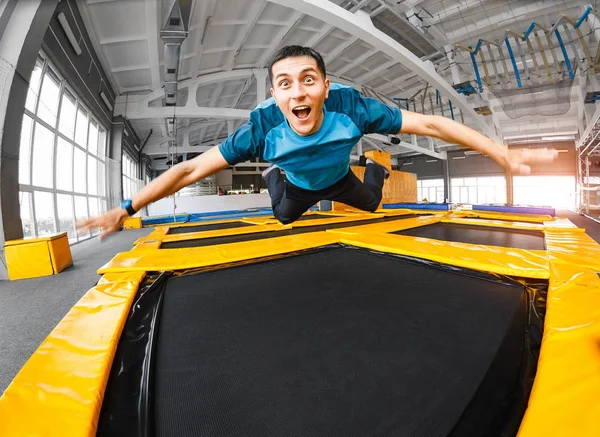 Um jovem apto homem feliz pulando e voando no trampolim no ginásio de fitness — Fotografia de Stock