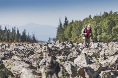 bir taş dağ eteğindeki taş yığını orman boyunca seyahat etmek sırt çantası ile yürüyor