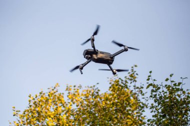 Modern siyah uzaktan denetim dron veya orman arka plan güçlü Rüzgar, uçan Quadcopter
