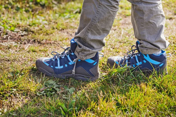 Botas de trekking oi-tech do miúdo em uma grama durante caminhadas ao ar livre — Fotografia de Stock