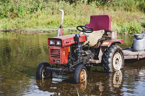 01 SEPTEMBER 2017, NIKOLAEVKA VILLAGE, BASHKORTOSTAN, RUSSIA: Old red tractor in water near the shore of the river — Stock Photo, Image