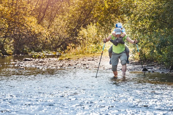 Baba ile oğlu güneşli sonbahar günü nehir çapraz. Aile Macera ve wade kavramı
