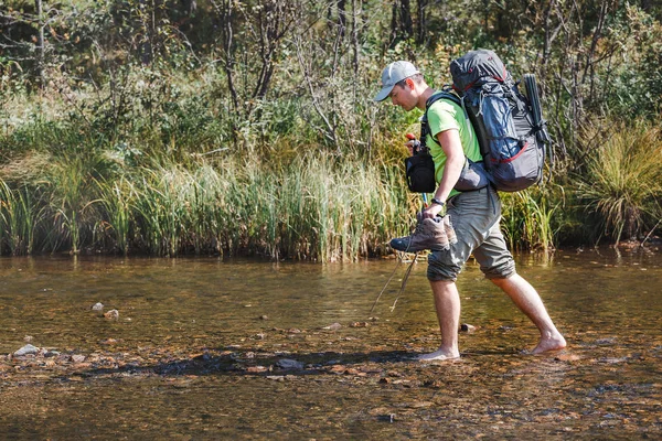 Escursionista escursionista guadare piccolo fiume di montagna, concetto di escursioni — Foto Stock