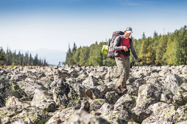 Viaggiatore con zaino cammina lungo un ghiaione di pietra nella foresta — Foto Stock