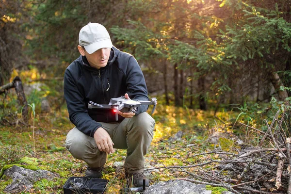 Un uomo lancia un moderno drone elicottero intelligente quartiere durante un'escursione attraverso la foresta — Foto Stock