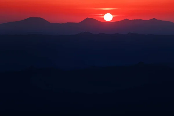 Ein wunderschöner farbenfroher Sonnenuntergang im Bergrücken mit glühend rotem Dunst — Stockfoto