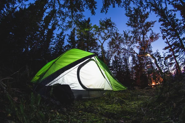 Campeggio turistico con una tenda e un fuoco di notte nella foresta, girato su una lente fisheye — Foto Stock