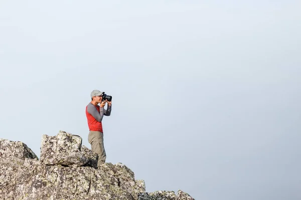Fotógrafo de naturaleza con cámara digital en la parte superior de la roca — Foto de Stock
