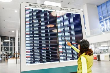 09 Eylül 2017, Kurumoch Kuf Airport, Samara, Rusya Federasyonu: arka görünümü güzel bir genç kadının ayakta ve havaalanında uçuşlar bir zamanlama ile elektronik çetele arıyorsunuz